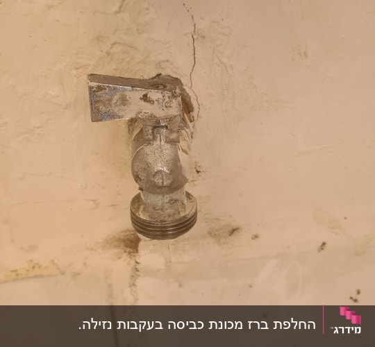 ברז מים ישן עם נזילה בקיר לבן